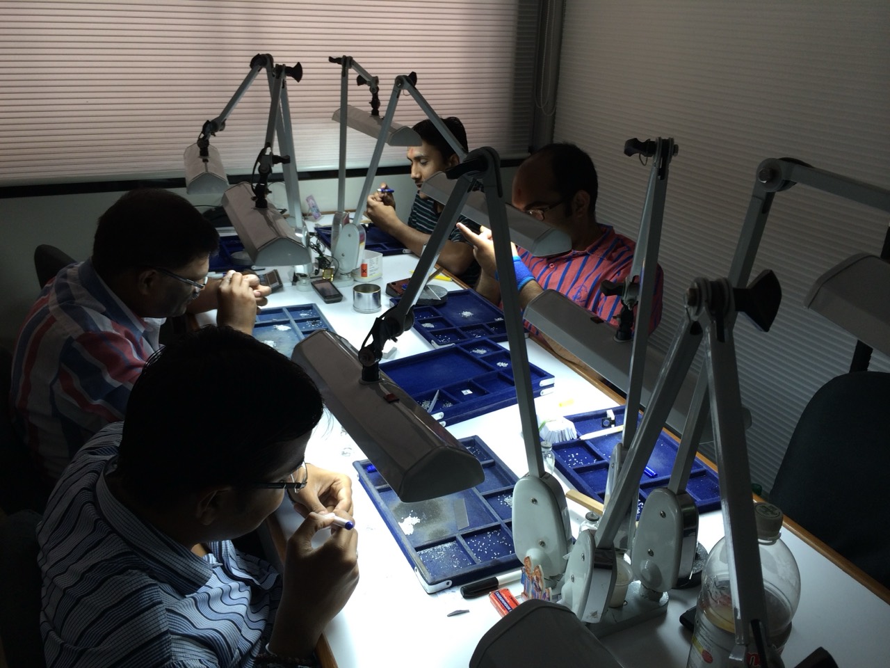 Diamond specialists working at illuminated inspection benches